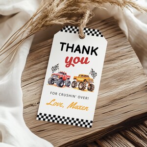 Puede incluir: Una etiqueta de regalo blanca con un borde a cuadros blanco y negro y una cuerda de hilo. La etiqueta dice "THANK YOU" en negro y rojo, con una ilustraci&oacute;n de acuarela de dos monster trucks. Tambi&eacute;n se incluye el texto "FOR CRUSHIN' OVER! Love, Maxen".