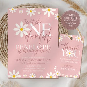 Può includere: Invito di compleanno rosa e tag di ringraziamento abbinato con accenti di margherita. L'invito recita "Isn't she wonderful, Penelope is turning One!" e include i dettagli dell'evento. Il tag dice "Thank You" con un messaggio personalizzato.