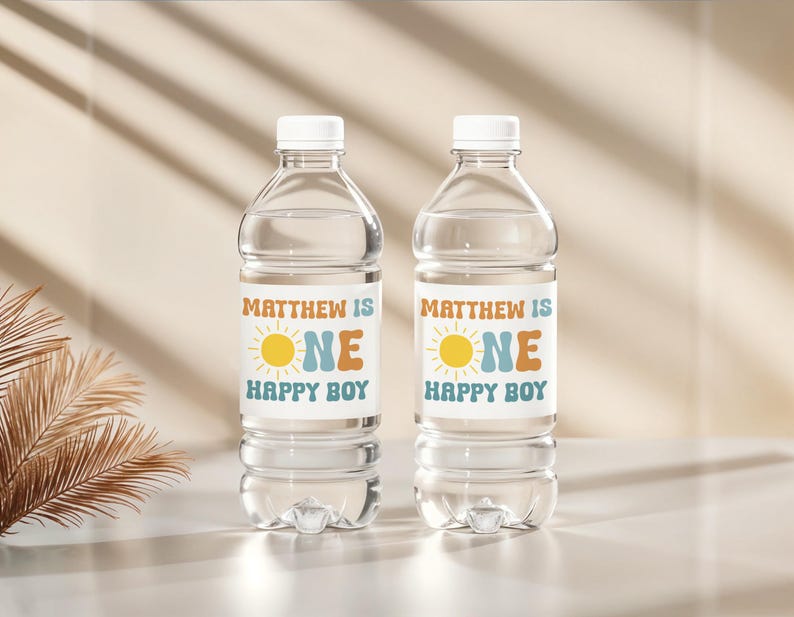 May include: Two clear plastic water bottles with white caps. Each bottle has a label that reads "MATTHEW IS ONE HAPPY BOY" with a sun graphic. The labels are in orange, blue, and yellow.
