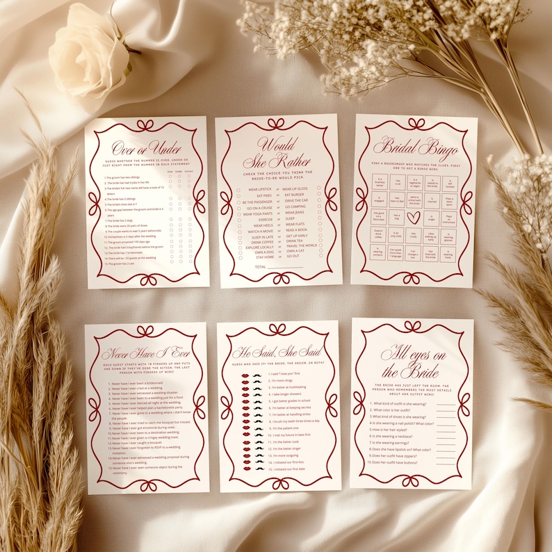 May include: Six ivory-colored bridal shower game cards with burgundy decorative borders and text. Games include "Over or Under," "Would She Rather," "Bridal Bingo," "Never Have I Ever," "She Said, She Said," and "All Eyes on the Bride."