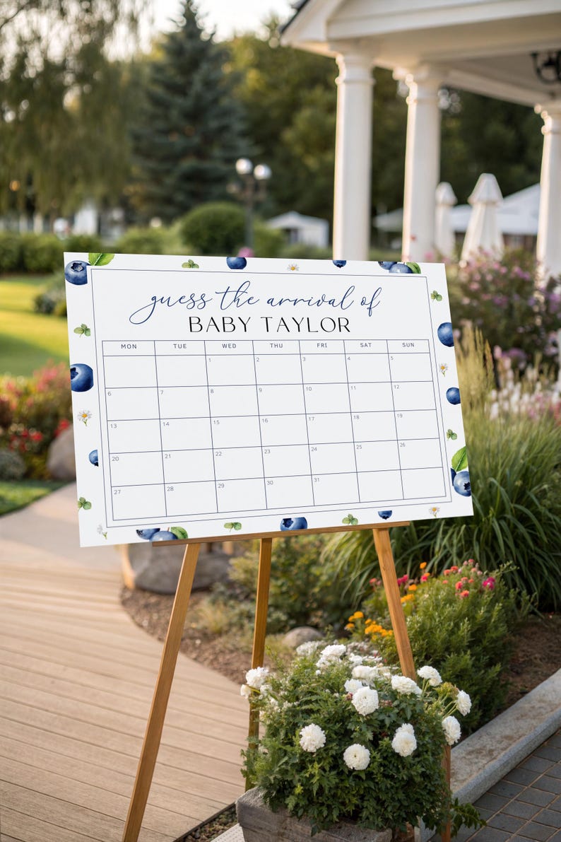 May include: A white sign on a wooden easel with the text "guess the arrival of BABY TAYLOR" and a calendar grid. The sign is decorated with blueberry and leaf illustrations. The easel is set up outdoors near flowers and greenery.