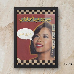 May include: Framed art print featuring a portrait of a woman with dark hair and red lipstick. The print includes Arabic text and a speech bubble with more text. The frame has a black and white checkered border.