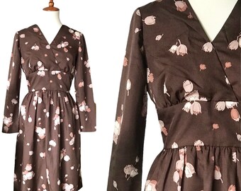 May include: A brown vintage dress with a V-neckline and long sleeves. The dress has a floral print with pink flowers on a brown background.
