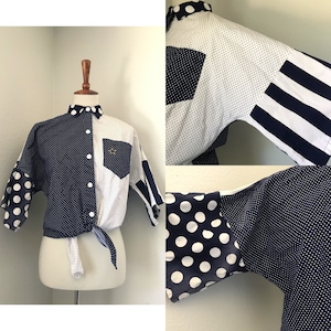 May include: A white and navy blue short-sleeved button-up shirt with a polka dot pattern and a striped pattern. The shirt has a tie at the waist.