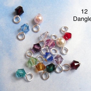 May include: Twelve assorted crystal and pearl dangles with silver loops. The dangles are in various colors, including red, blue, green, purple, and pink.