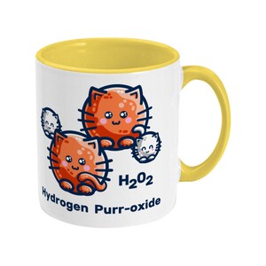 K&ouml;nnte beinhalten: Eine wei&szlig;e Keramiktasse mit gelbem Rand und Henkel. Die Tasse zeigt eine Cartoon-Illustration von drei orangefarbenen Katzen mit dem Text "H2O2 Hydrogen Purr-oxide".