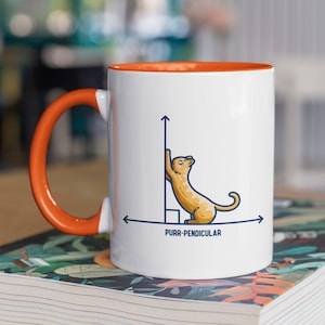 May include: White ceramic mug with an orange rim. The mug features a cartoon cat leaning against a vertical line with an arrow pointing upwards. The horizontal line has an arrow pointing to the right and the text "PURR-PENDICULAR".