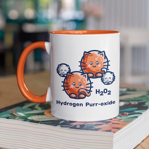 K&ouml;nnte beinhalten: Wei&szlig;e Keramiktasse mit orangefarbenem Rand und Henkel. Die Tasse zeigt eine Cartoon-Illustration von orangefarbenen Katzen mit dem Text "H2O2 Hydrogen Purr-oxide".