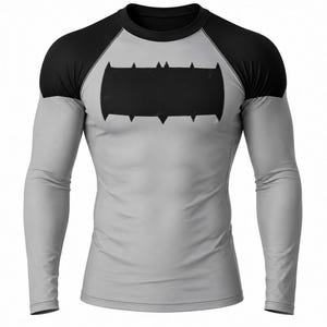 May include: A gray long-sleeve shirt with black sleeves and a black emblem on the chest. The emblem is a stylized bat symbol. The shirt is form-fitting and likely made of a stretchy material, suitable for athletic wear or cosplay.
