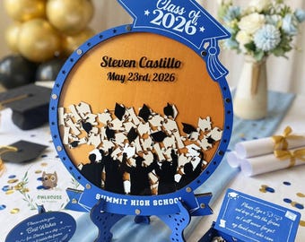 Op de afbeelding: Een blauwe en gouden afstudeer schaduwdoos met de tekst "Class of 2026" en "Steven Castillo May 23rd, 2026". De lijst heeft een uitgesneden ontwerp van afgestudeerden. Inclusief een aanmeldbox en een klein bordje met "Sign here!"