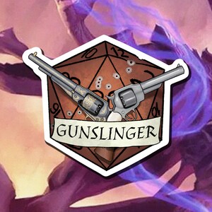 May include: A brown, six-sided die with a pair of silver revolvers crossed over it. The die has bullet holes and the text "GUNSLINGER" is written on a banner below the revolvers.
