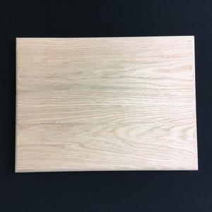 May include: A light wood cutting board with a smooth surface and a natural grain pattern.