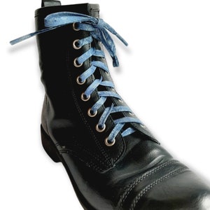 May include: Black leather boots with blue glitter shoelaces. The laces are tied in a criss-cross pattern.