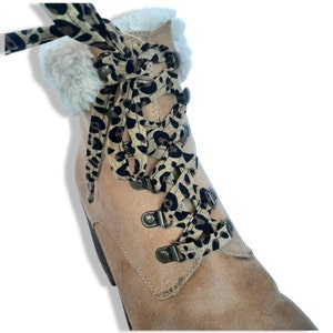May include: Tan suede boot with faux fur trim and leopard print laces. The boot features metal eyelets and a sturdy design, suitable for various outdoor activities. The laces are tied in a decorative bow.