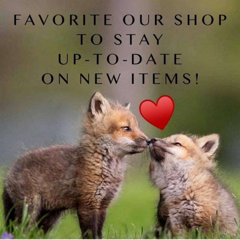 May include: Two fox kits, one brown and one tan, touch noses in a grassy field. A red heart graphic is above them. Text at the top reads, "FAVORITE OUR SHOP TO STAY UP-TO-DATE ON NEW ITEMS!"