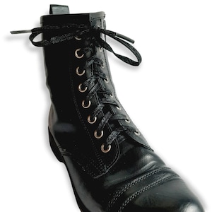 May include: Black leather lace-up boots with silver eyelets. The boots have a rounded toe and a thick sole.