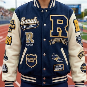 Può includere: Una giacca college blu navy e crema con diverse toppe. La giacca presenta il nome "Sarah" e "EST. 2024" sopra un logo "R" dorato. Le toppe includono "TRACK & FIELD", "ELITE RUNNER" e "DISTRICT CHAMP".
