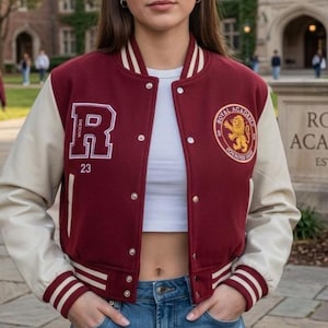 Può includere: Giacca college bordeaux e crema con la lettera "R" e il numero "23" sul davanti. La giacca ha una toppa "Royal Academy" con un'emblema del leone. Colletto e maniche bianche.