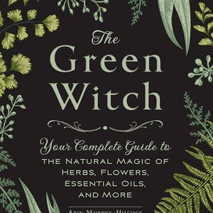 May include: A book cover with the title "The Green Witch" in large, light green letters. The cover is black with green botanical illustrations around the edges. The text "Your Complete Guide to the Natural Magic of Herbs, Flowers, Essential Oils, and More" is also included.
