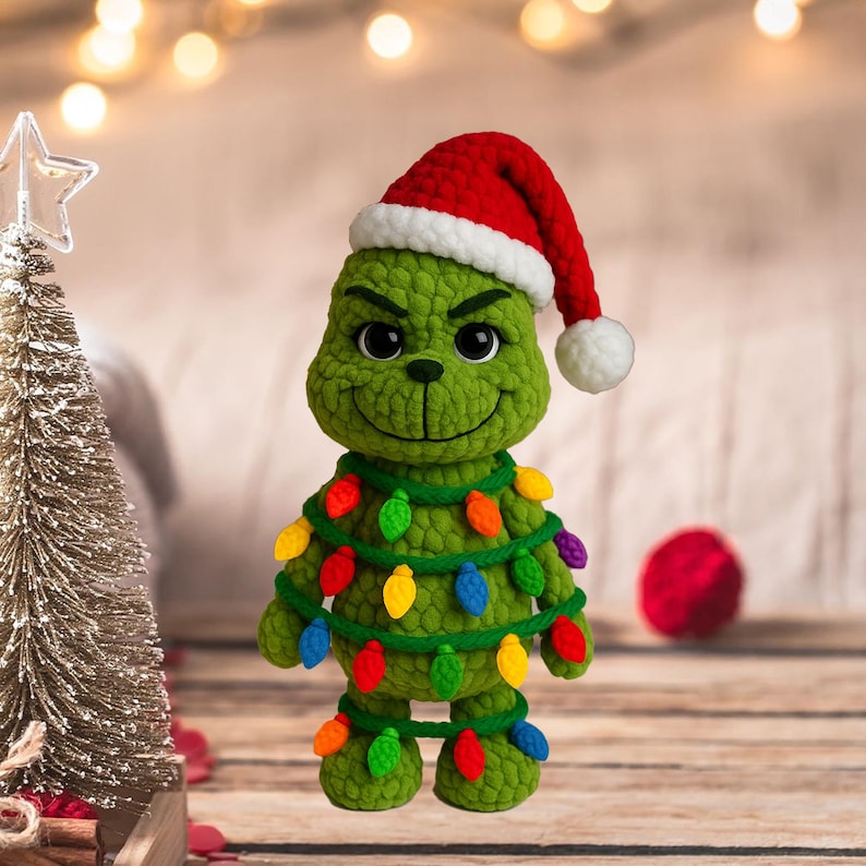 May include: A handmade green crochet Grinch figure wearing a red Santa hat with a white trim and a white pom-pom. The Grinch is adorned with a string of colorful Christmas lights, perfect for holiday decor.