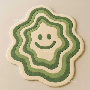 May include: A green and cream-colored rug with a wavy, abstract design. The rug features a large, smiling face in the center.