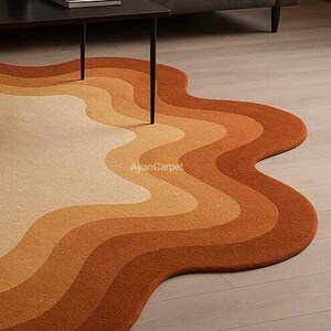 May include: A wavy, abstract area rug with a multi-colored design in shades of orange, brown, and cream. The rug is made of soft, plush material and has a unique, organic shape.