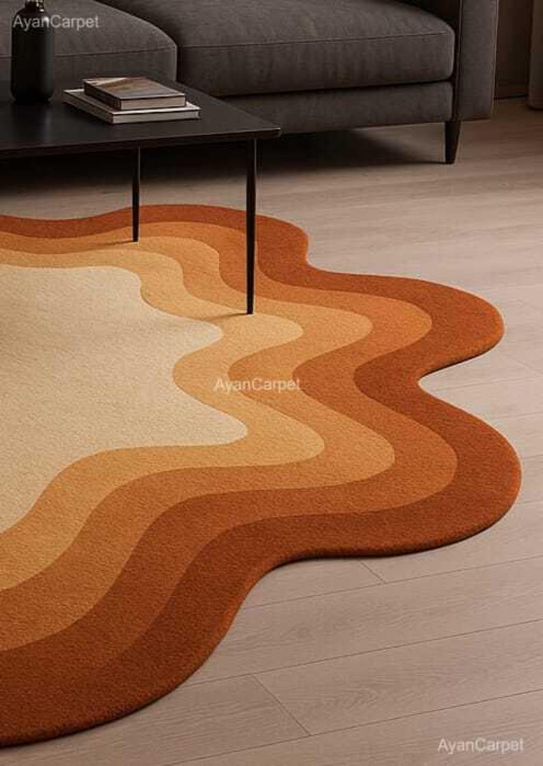 May include: A wavy, abstract area rug with a multi-colored design in shades of orange, brown, and cream. The rug is made of soft, plush material and has a unique, organic shape.