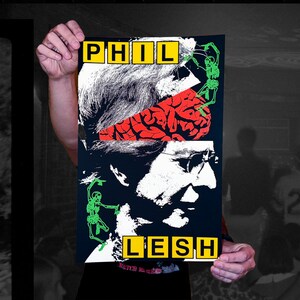 May include: A poster with a black background featuring a white and red illustration of a person's face and brain. The name "PHIL LESH" is displayed in yellow block letters. Green skeleton figures are also present.