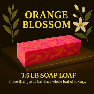 May include: A vibrant, rectangular soap loaf with a pink and orange swirl pattern. The text "ORANGE BLOSSOM" is above the soap, and "3.5 LB SOAP LOAF" is below. The background is dark with floral accents.