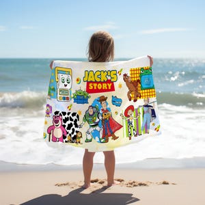 May include: A white beach towel featuring various Toy Story characters and the text "JACK'S STORY". The towel has a colorful design with images of Woody, Buzz Lightyear, and other characters from the animated film.