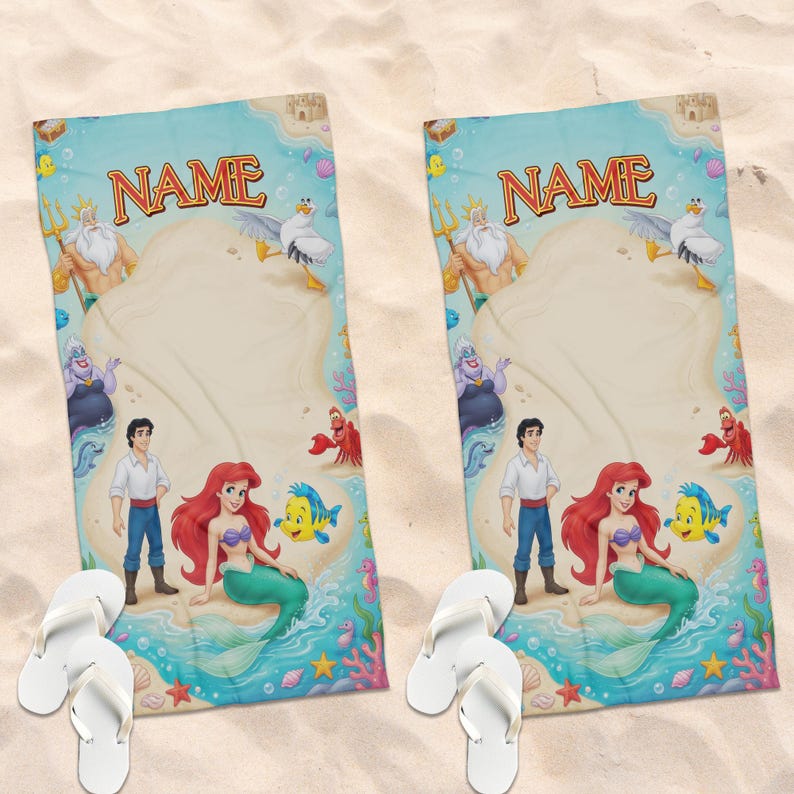 May include: Two beach towels featuring characters from The Little Mermaid, including Ariel. The towels have a light blue border with the word "NAME" in gold. White flip-flops are in the foreground, on a sandy surface.