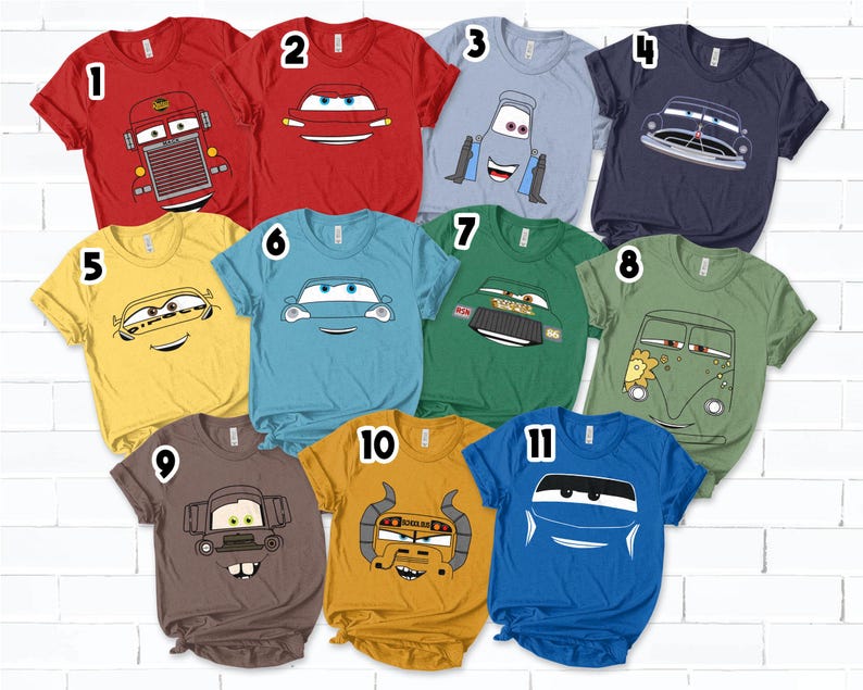 May include: A collection of eleven short-sleeved t-shirts in various colors, each featuring a cartoon car design. The shirts are red, yellow, blue, green, and brown. The car designs vary, with different expressions and styles.