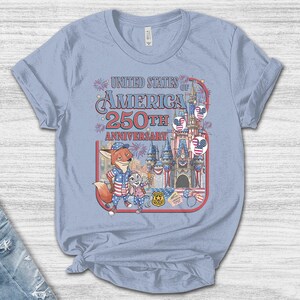 Puede incluir: Camiseta azul claro con un gr&aacute;fico colorido que celebra el 250 aniversario de los Estados Unidos de Am&eacute;rica. El dise&ntilde;o incluye personajes de dibujos animados, un castillo y elementos patri&oacute;ticos.