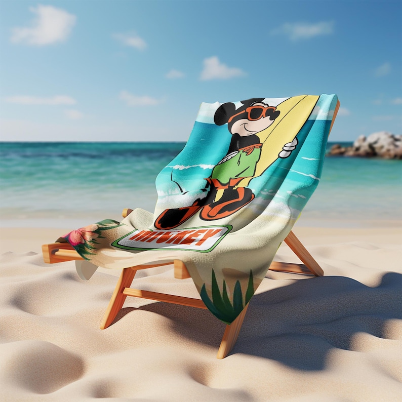 K&ouml;nnte beinhalten: Ein Strandtuch auf einem h&ouml;lzernen Liegestuhl mit einer Grafik von Mickey Mouse, der eine orangefarbene Sonnenbrille und eine gr&uuml;ne Shorts tr&auml;gt und ein gelbes Surfbrett h&auml;lt. Das Tuch zeigt einen blauen Ozeanhintergrund und den Schriftzug MICKEY.