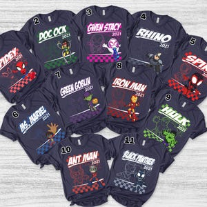 Pode incluir: Uma cole&ccedil;&atilde;o de onze camisetas azul-marinho escuro, cada uma com um gr&aacute;fico de personagem Marvel &uacute;nico, o nome do personagem e o ano 2021. Os personagens incluem Spidey, Doc Ock, Gwen Stacy, Rhino, Spin, Ms. Marvel, Green Goblin, Iron Man, Hulk, Ant Man e Black Panther.
