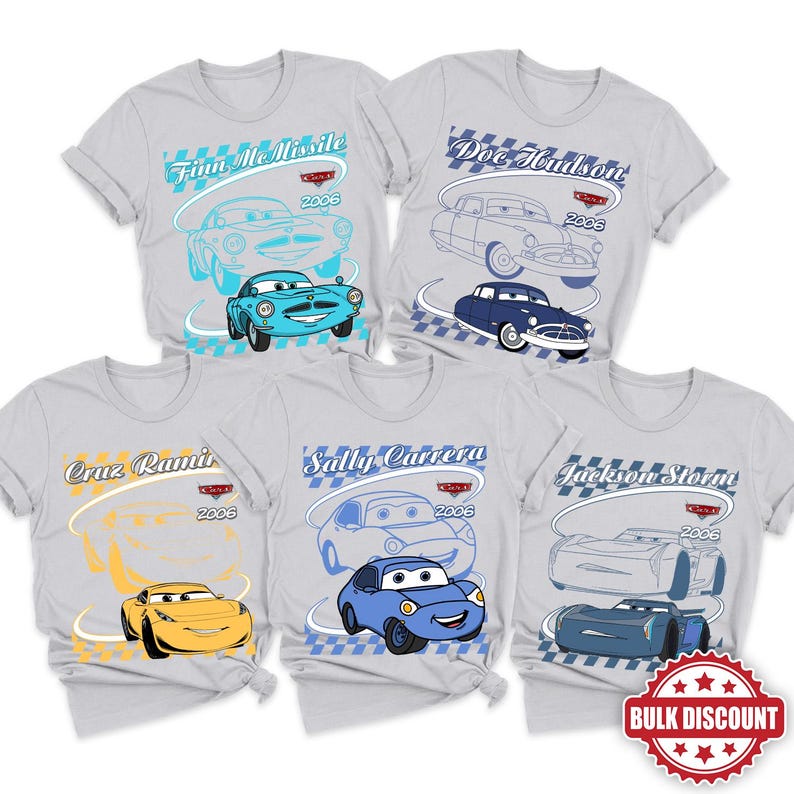 Peut inclure: Cinq t-shirts gris clair avec des personnages de Disney Pixar Cars. Chaque t-shirt affiche un nom de personnage, l'ann&eacute;e 2006, un logo Cars et une illustration en couleur de Finn McMissile, Doc Hudson, Cruz Ramirez, Sally Carrera ou Jackson Storm.