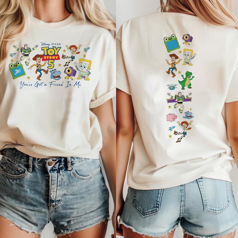 May include: A cream-colored t-shirt featuring Toy Story 5 graphics. The front displays characters, the logo, and the text "You've Got a Friend In Me." The back features a vertical column of various Toy Story character illustrations and icons.
