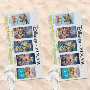 May include: A white beach towel featuring the Disney Pixar Toy Story movie franchise posters from 1995 to 2026, with the text YOU'VE GOT A FRIEND printed vertically in yellow, accompanied by a pair of white flip-flops placed at the bottom.