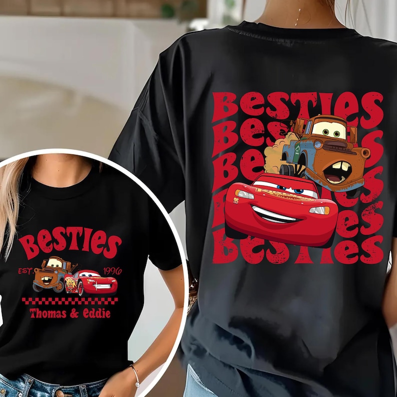 Może przedstawiać: Czarne koszulki z czerwonym nadrukiem postaci Zygzaka McQueena i Złomka z filmu Auta. Słowo "Besties" jest wydrukowane na czerwono, wraz z imionami "Thomas & Eddie".