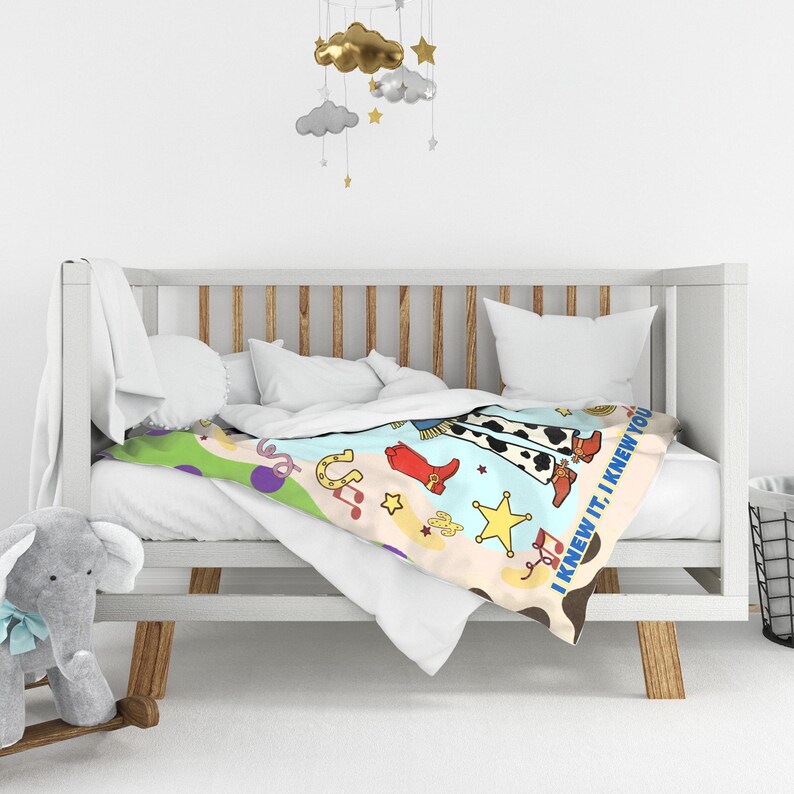 May include: A soft blanket featuring a colorful western-themed print with cow print patterns, red cowboy boots, yellow stars, horseshoes, and musical notes. The text "I KNEW IT, I KNEW YOU" is printed along the edge of the fabric in blue letters.