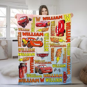 Puede incluir: Una colorida manta con el personaje Rayo McQueen de la pel&iacute;cula Cars. La manta tiene un fondo degradado e incluye el nombre "William" y el n&uacute;mero "95" en varios dise&ntilde;os. La manta es una vibrante mezcla de rojo, amarillo y azul.