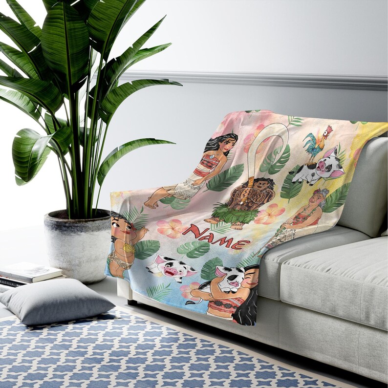 Puede incluir: Una colorida manta con personajes de dibujos animados y elementos tropicales. La manta muestra varios personajes, flores y la palabra "NAME" en una fuente l&uacute;dica. El dise&ntilde;o est&aacute; sobre un fondo pastel.