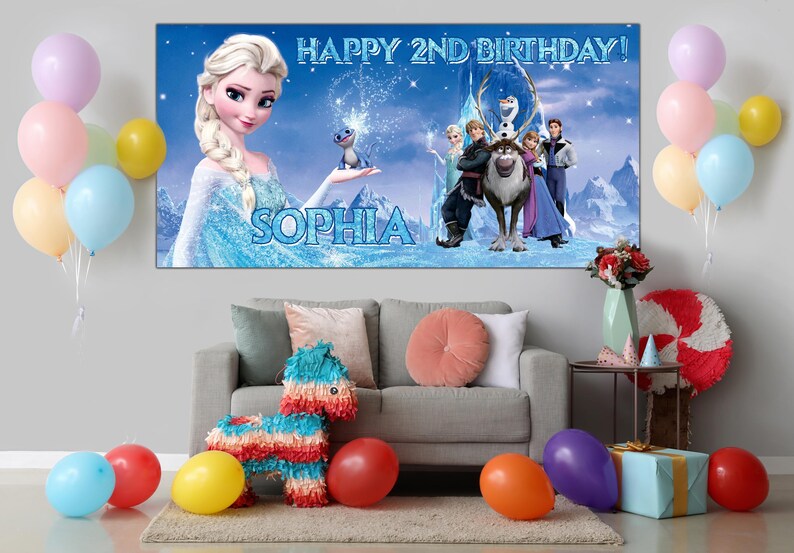 Puede incluir: Una pancarta de cumplea&ntilde;os con el texto "HAPPY 2ND BIRTHDAY!" y el nombre "SOPHIA" presenta personajes de la pel&iacute;cula Frozen. La escena incluye a Elsa, Anna, Olaf, Kristoff y Sven. Globos y decoraciones de fiesta completan el ambiente festivo.