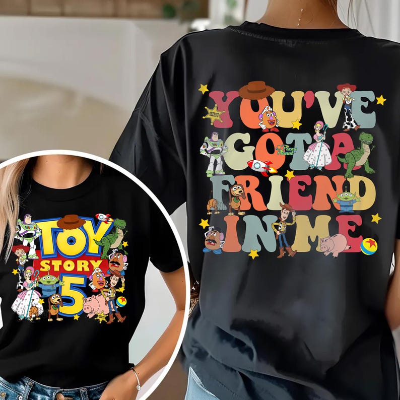 K&ouml;nnte beinhalten: Schwarzes T-Shirt mit einem farbenfrohen Grafikdesign aus dem Film "Toy Story". Das Design auf der Vorderseite zeigt "Toy Story 5" mit verschiedenen Charakteren. Auf der R&uuml;ckseite steht "You've Got A Friend In Me".
