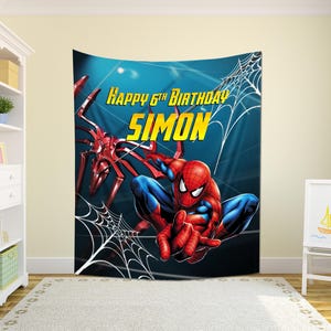 May include: A large wall tapestry featuring Spider-Man in a dynamic pose, with a red and blue costume. The background is a gradient of blue. Text reads "Happy 6th Birthday Simon" in yellow. A spider web design is also present.