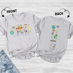 May include: A light gray t-shirt shown from the front and back. The front features Toy Story 5 branding with characters and the text You've Got a Friend In Me. The back displays a vertical arrangement of various Toy Story character illustrations.