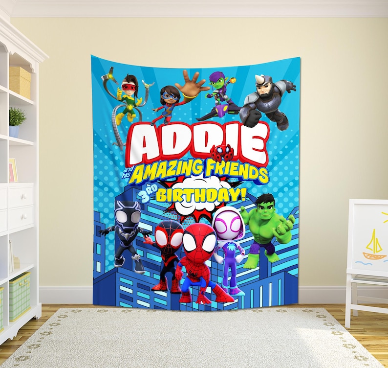 May include: A blue tapestry featuring cartoon characters and the text "Addie and his Amazing Friends 3rd Birthday!". The design includes illustrations of Spider-Man, Hulk, and other superheroes, set against a cityscape backdrop.