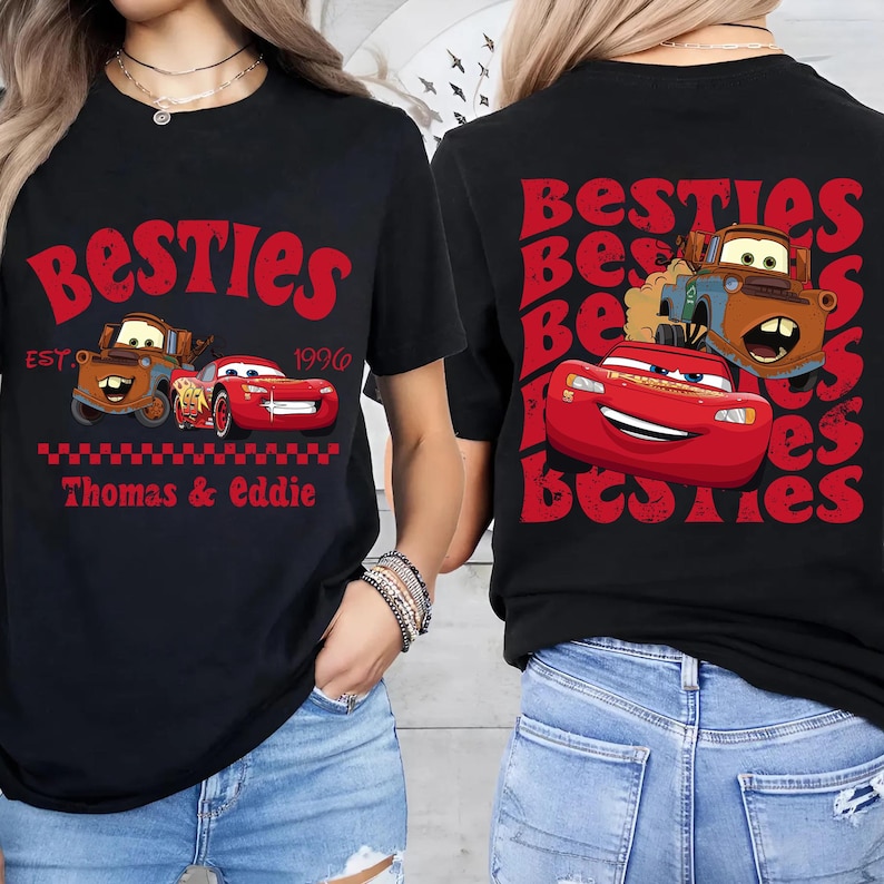 Może przedstawiać: Czarna koszulka z czerwonym nadrukiem z napisem "Besties" i samochodami z kresk&oacute;wek. Projekt z przodu zawiera tekst "Thomas & Eddie" i "Est. 1996". Tył koszulki r&oacute;wnież ma napis "Besties" i samochody z kresk&oacute;wek.