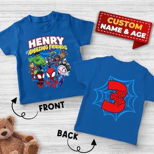 May include: A blue short-sleeved t-shirt featuring a graphic of Marvel characters and the text "HENRY and his AMAZING FRIENDS" on the front, and a large red number "3" with a spiderweb design on the back, with a red tag labeled "CUSTOM NAME & AGE".