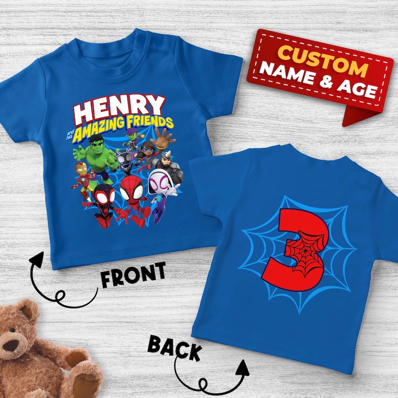 May include: A blue short-sleeved t-shirt featuring a graphic of Marvel characters and the text "HENRY and his AMAZING FRIENDS" on the front, and a large red number "3" with a spiderweb design on the back, with a red tag labeled "CUSTOM NAME & AGE".